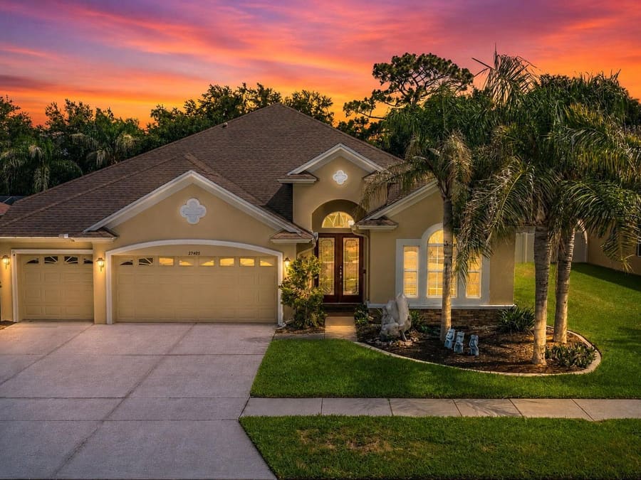 Front elevation at sunset of the four-bedroom pool home at 27405 Sora Blvd, Wesley Chapel